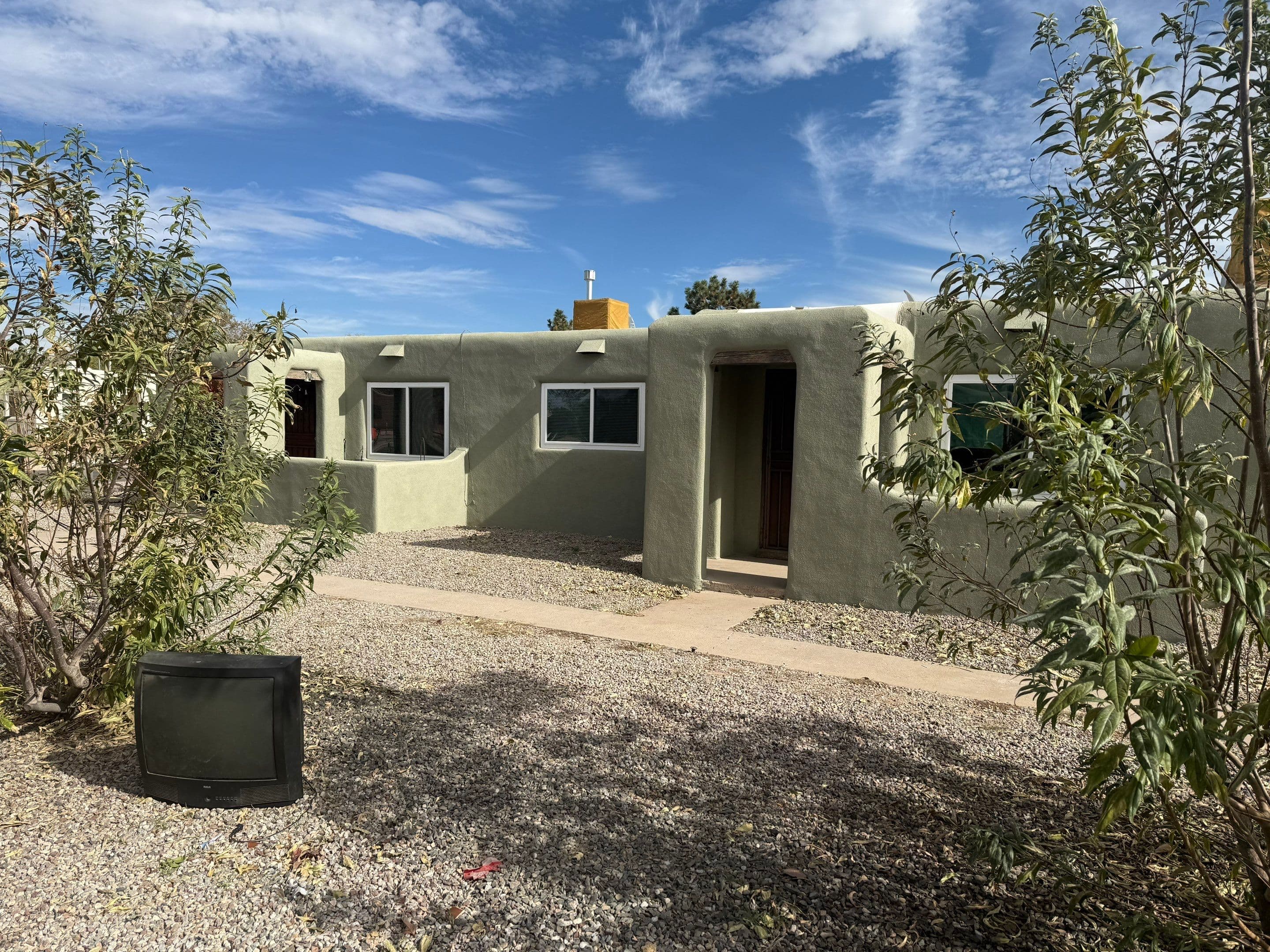 Wider view of the same Albuquerque home after window replacement, framed by mature trees
